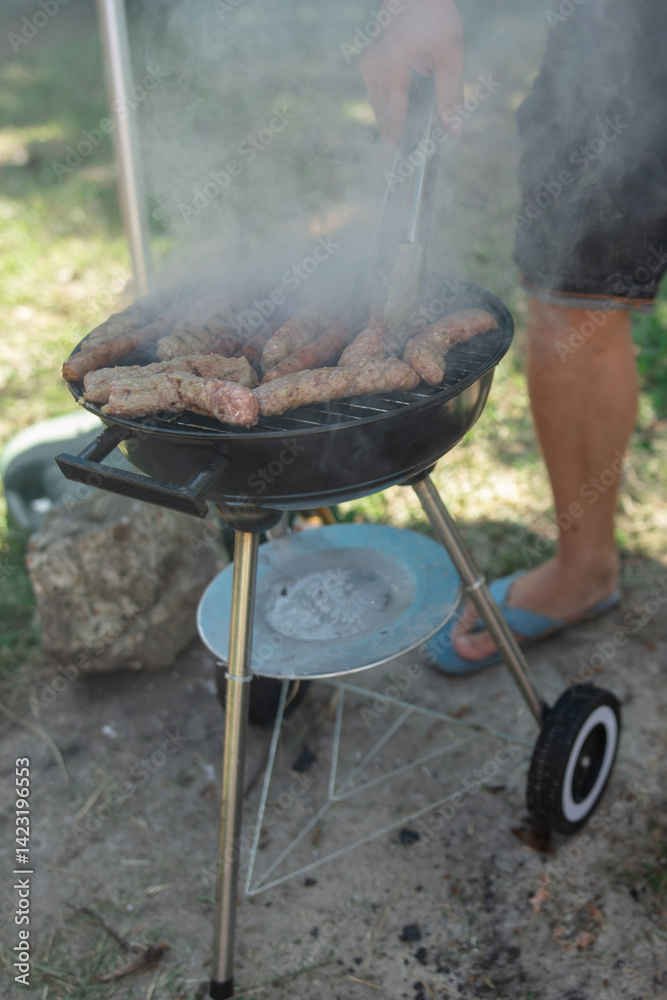 Man preparing barbeque in the garden on a hot summer day.