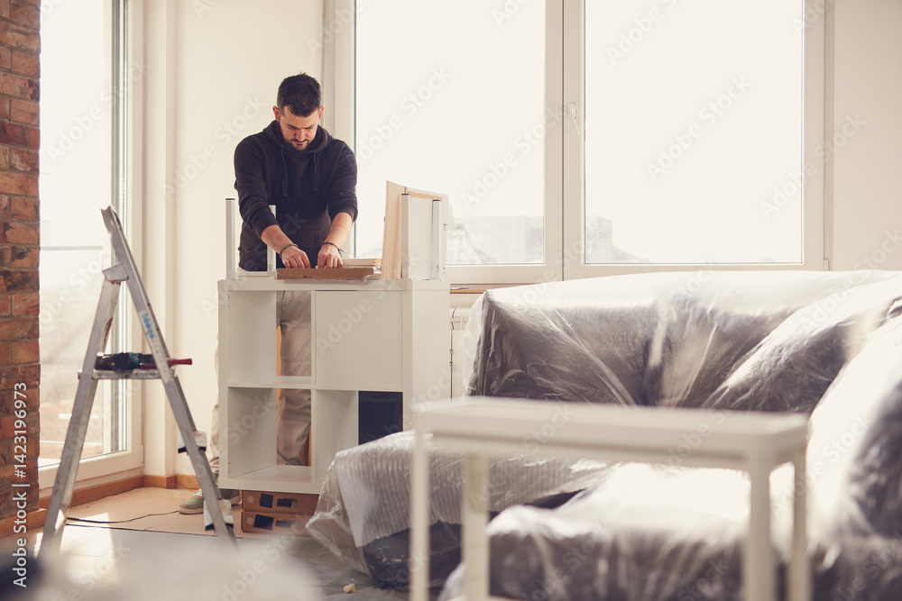 Man working and assembling furniture in a new apartment.