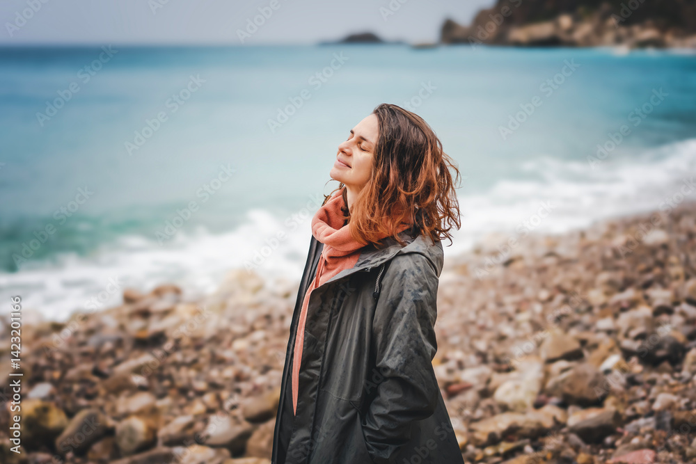 Young relaxed woman enjoying sea breeze in rainy weather