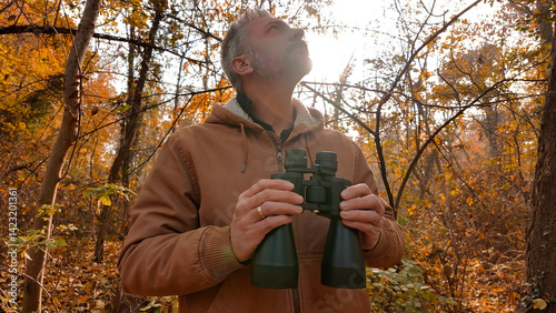 Obraz na płótnie Amateur birdwatcher observing birds and other animals in nature with binoculars. w salonie