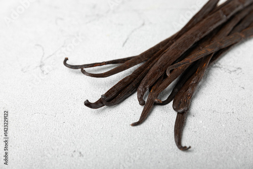 Fototapeta Naklejka Na Ścianę i Meble -  Vanilla pods on a textured background. Vanilla flowers and seeds. vanilla stick bean. Aromatic spicy spice for pastries and desserts. Seasoning. Space for text. Copy Space