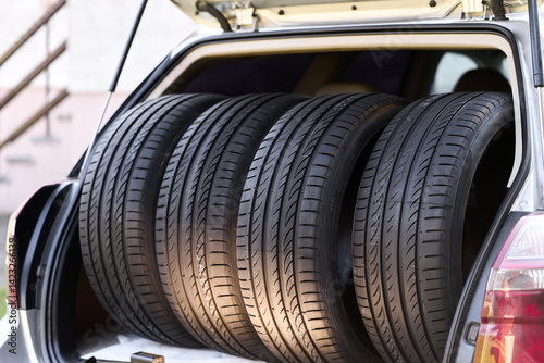 Four summer tires placed in open car trunk
