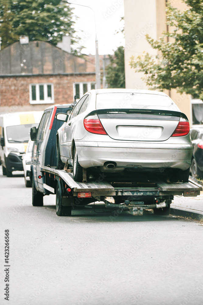 Tow truck transporting broken car in urban area
