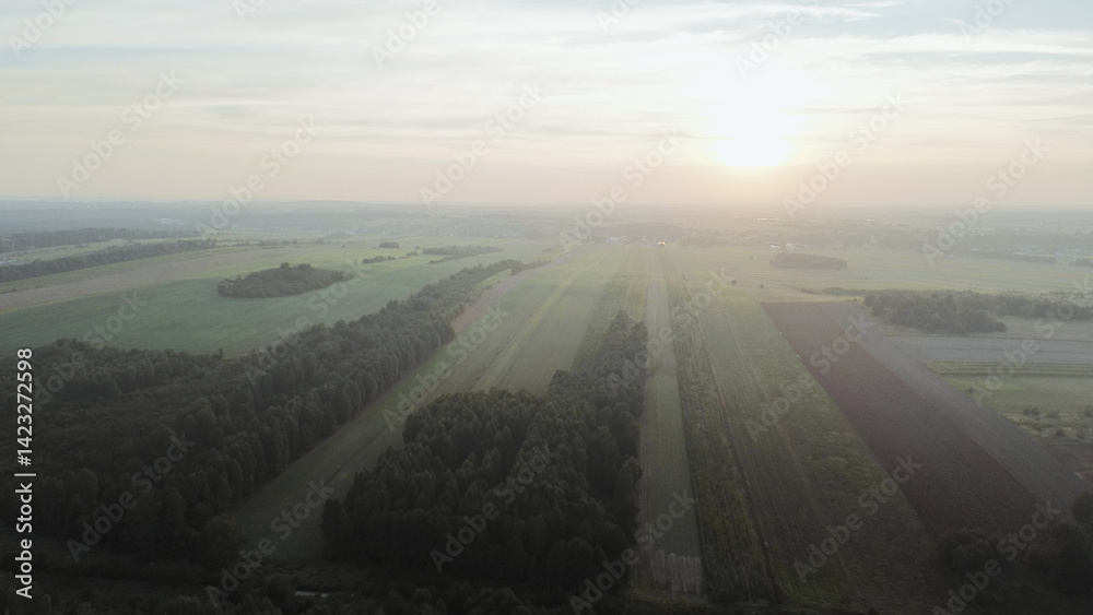 Aerial view of foggy autumn forest with fields and village