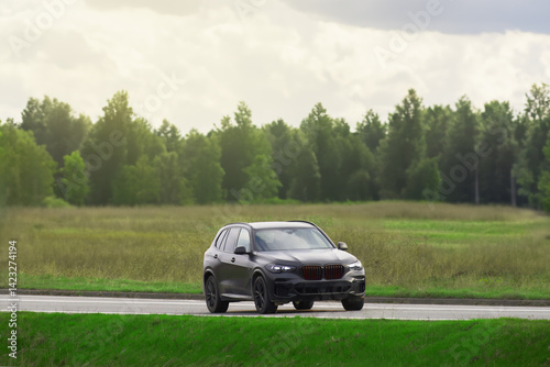 Obraz na płótnie Expensive black SUV on a scenic road with lush green fields w salonie