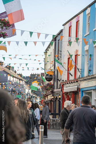 Festive street scene in Galway, Ireland, with colorful facades, Irish flags, and people walking under strings of bunting on a lively evening.
