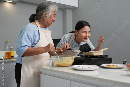 Obraz na płótnie Two women, daughter cooking with elderly mother at home, happy mother's day, family day w salonie