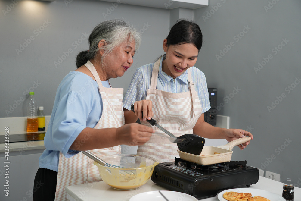 Two women, daughter cooking with elderly mother at home, happy mother's day, family day