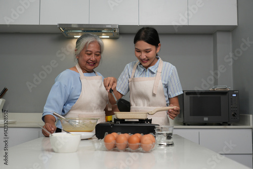 Two women, daughter cooking with elderly mother at home, happy mother's day, family day