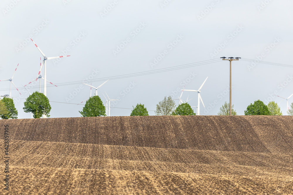 Ein Feld Acker mit Windenergieanlegen dahinter