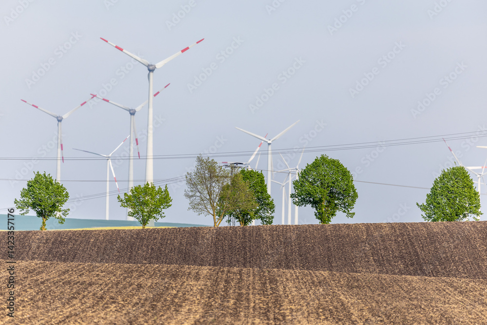 Ein Feld Acker mit Windenergieanlegen dahinter