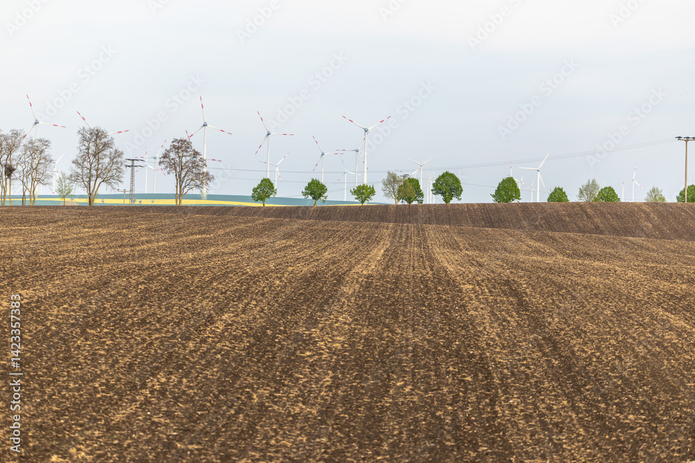 Ein Feld Acker mit Windenergieanlegen dahinter
