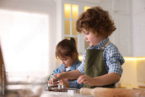 Cooking recipe. Little children cutting cookies with cutters at table in kitchen. Space for text