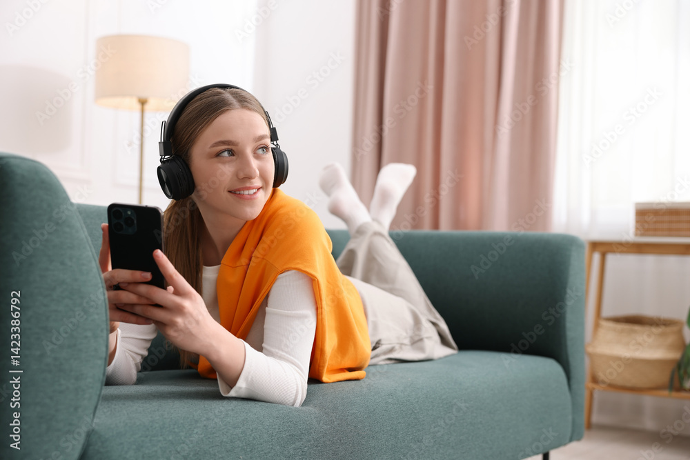 Smiling teenage girl with smartphone on sofa at home Smiling teenage girl with smartphone on sofa at home