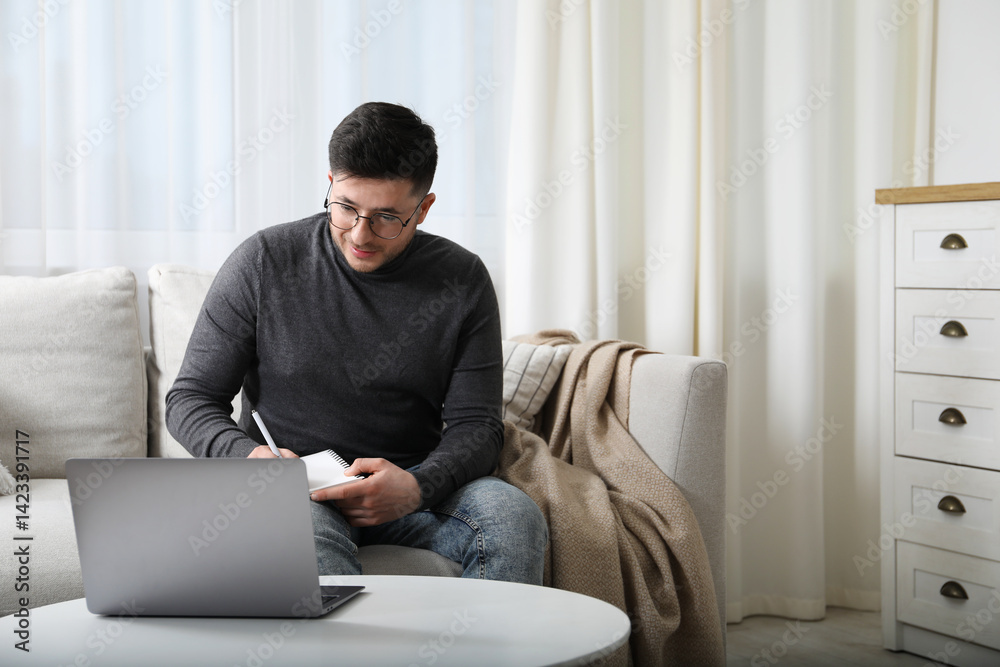 Man taking notes during online lesson at table indoors, space for text. Self-study Man taking notes during online lesson at table indoors, space for text. Self-study