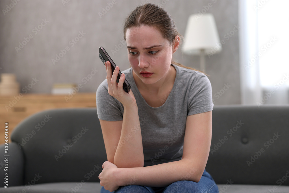 Depressed woman calling hotline for mental health help on sofa at home