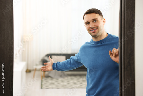 Fotografija Cheerful man welcoming guests to his apartment. Space for text