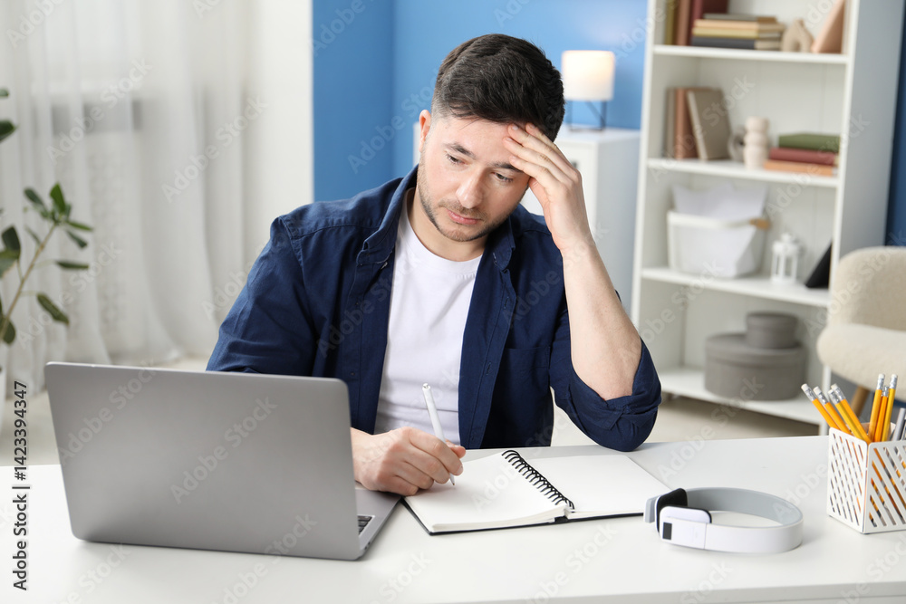 Man taking notes during online lesson at desk indoors. Self-study Man taking notes during online lesson at desk indoors. Self-study
