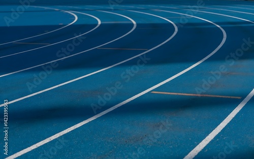 A blue running track with white lines, curving towards the horizon, symbolizing the pursuit of goals and progress.
