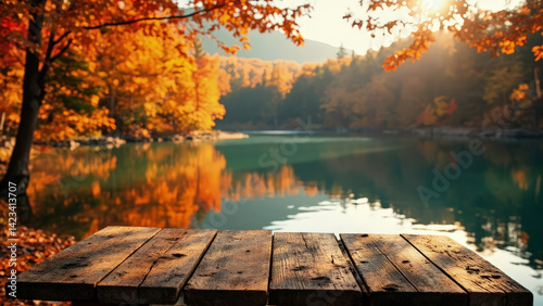 An autumn landscape with a wooden surface in the front, a stunning lake with the mountains and trees. The foliage has turned into beautiful autumn colors, with a vibrant mix of oranges, reds.