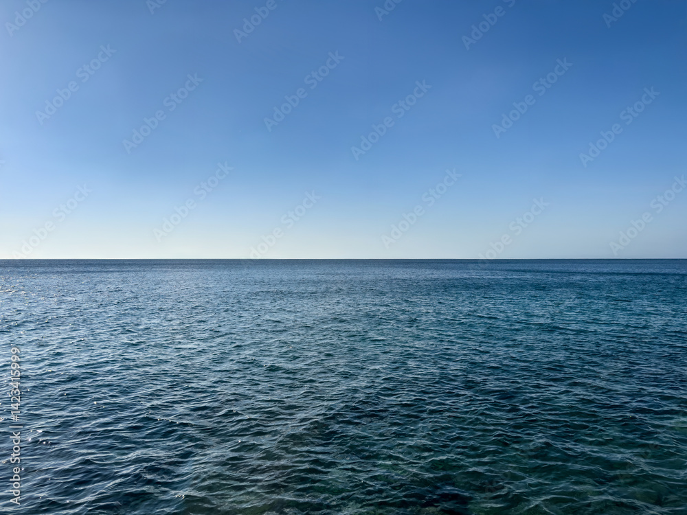 Fototapeta premium calm sea under bright clear sky with copy space. solid blue background. minimalist sea background. straight lines. nature balance. deep