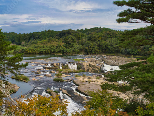 Sogi Waterfalls flowing through striking rock formations in Kyushu, Japan, surrounded by forest and greenery.
