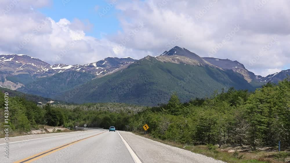 Slow motion video taken from a moving car on the scenic route to Ushuaia, in this section there are native forests to the left and right and in front large mountains