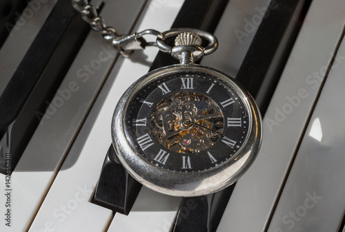 Antique pocket watch or Retro pocket watch on Piano keys background. 
