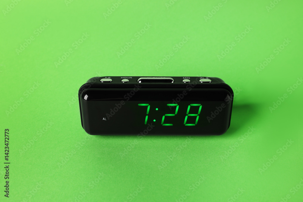 Digital alarm clock showing 7:28 o'clock on green background
