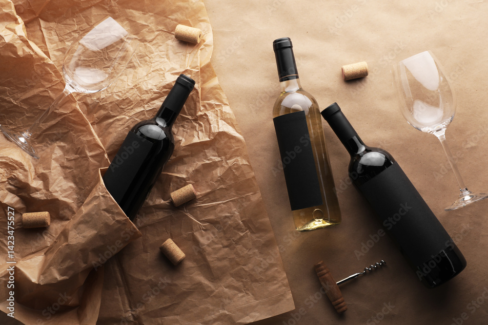 Bottles of wine, glasses, corkscrew and corks on parchment paper, flat lay
