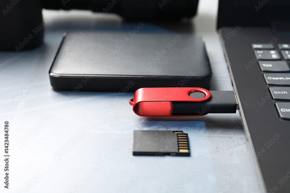 Flash drive connected to laptop, SD memory card and external hard disk on gray table, closeup Flash drive connected to laptop, SD memory card and external hard disk on gray table, closeup