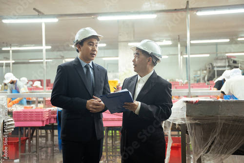 A businessman discussing with business partner at fish factory. Entrepreneur inspecting at food processing in manufacturing line production.
