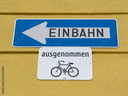 German one-way street sign with bicycle exception on yellow wall