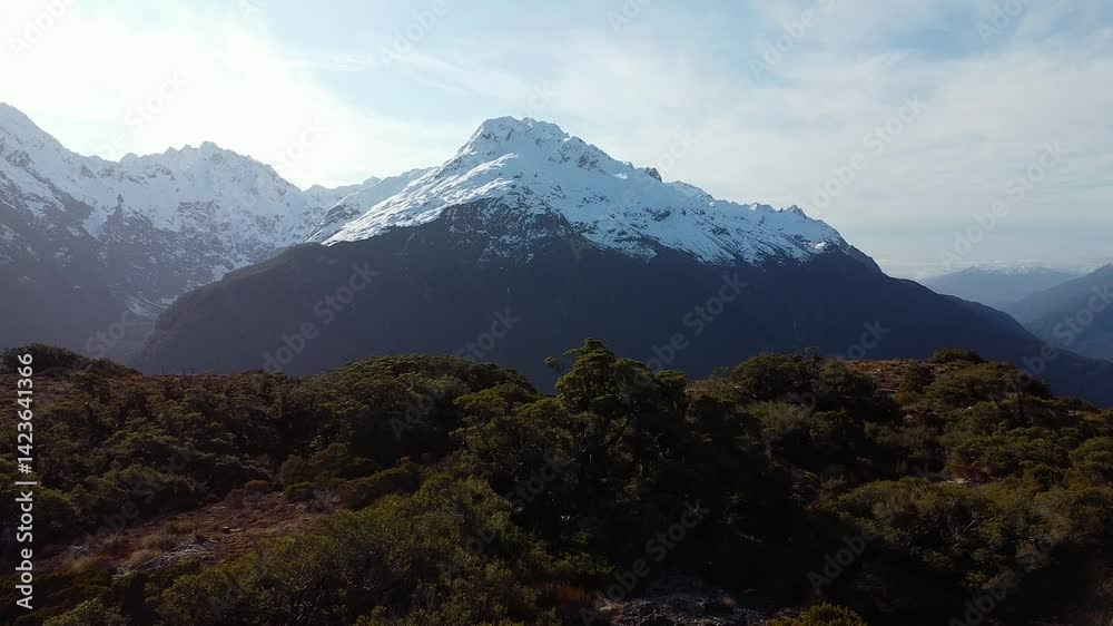 Sunny drone ascends over Key Summit in New Zealand's Fiordland with clear skies and snow peaks, aerial establishing Sunny drone ascends over Key Summit in New Zealand's Fiordland with clear skies and snow peaks, aerial establishing