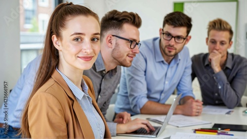 Team portrait full of ambition for success in a bright meeting room with a smiling young woman looking at the camera while a diverse young business team works collaboratively in the background