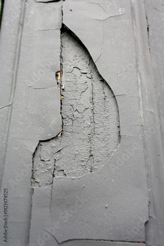 Décollement d'enduit sur un mur dissimulé avec une peinture grise