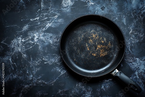 Top view of a non-stick frying pan on a dark blue marble kitchen countertop
