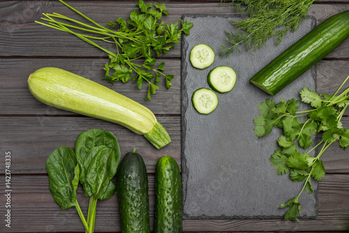 Obraz na płótnie Sliced cucumber, cilantro and dill on cutting board. Zucchini, spinach and parsley on table w salonie