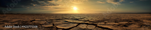 Wide panorama of desolate cracked terrain with the sun faintly visible through the dust storm, drought and desertification concept.
