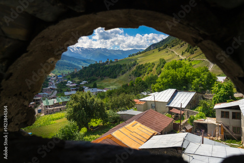 Breathtaking view of mestia village and surrounding caucasus mountains from ancient svaneti defensive tower in upper svaneti region, georgia, under a beautiful blue sky with white clouds