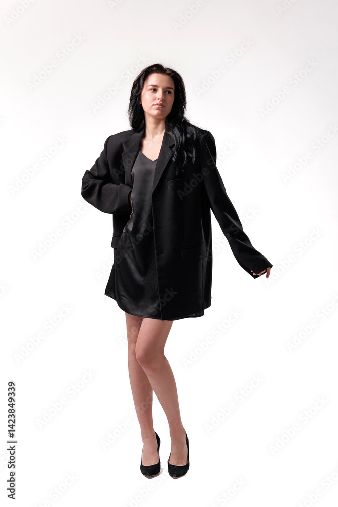 Fashion model poses in oversized blazer on plain background during studio shoot Fashion model poses in oversized blazer on plain background during studio shoot