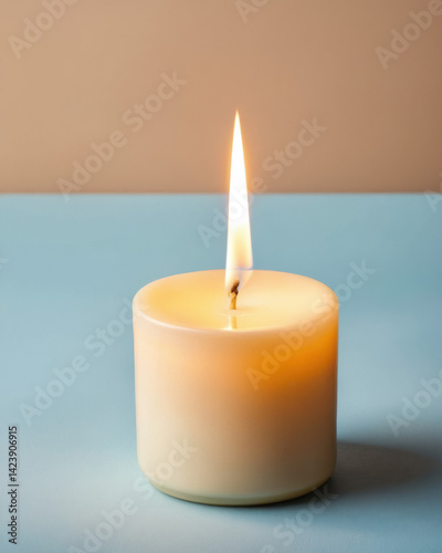 A serene close-up of a lit candle on a blue surface, casting a warm glow against a subtle background.