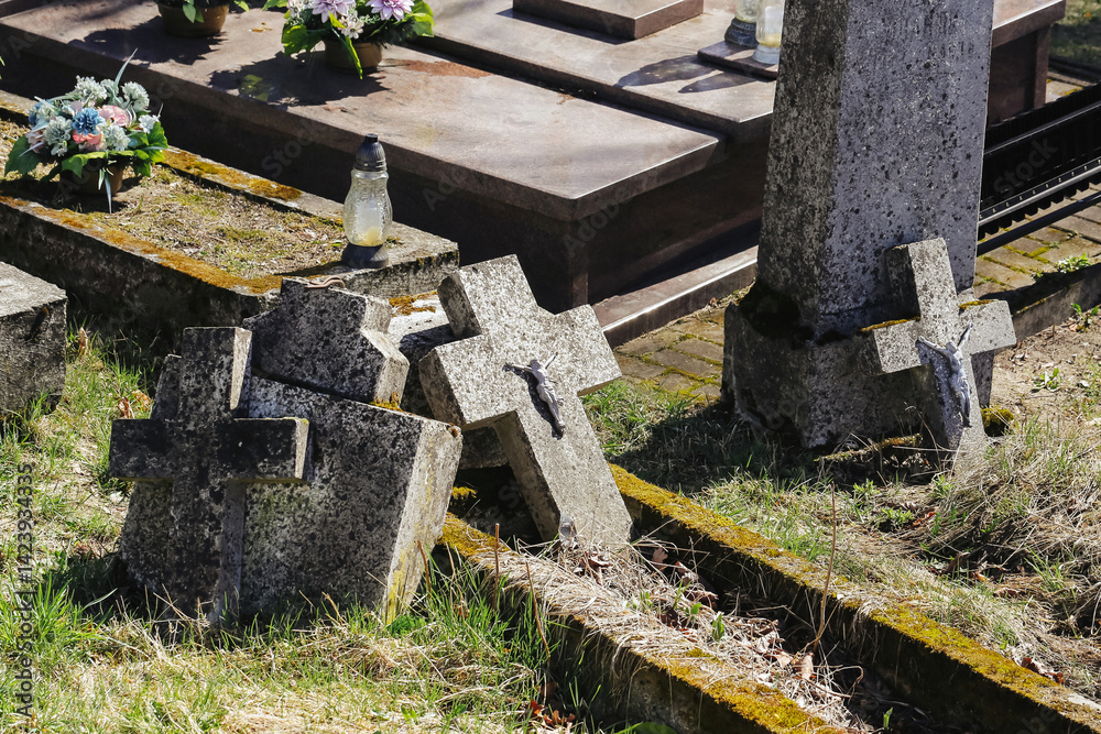 Old cemetery crosses. Weathered graves. Forgotten resting place. Stone tombs in sunlight. Religious symbols decay. Historic burial site. Spiritual silence. Death and memory. Abandoned graveyard view.