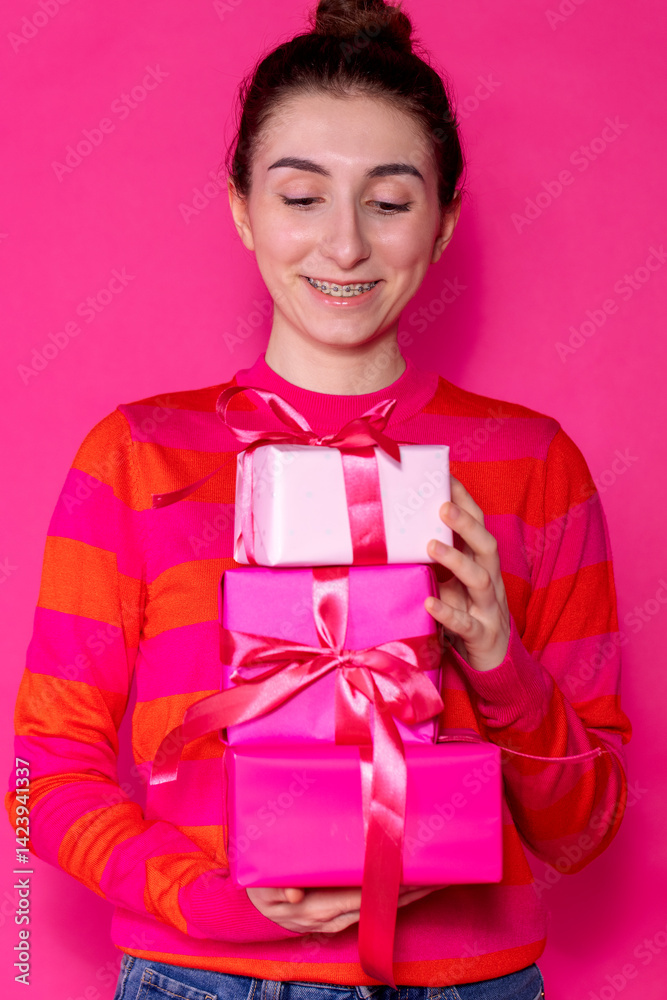 Half of the girl in a pink sweater with gifts on a pink background Half of the girl in a pink sweater with gifts on a pink background