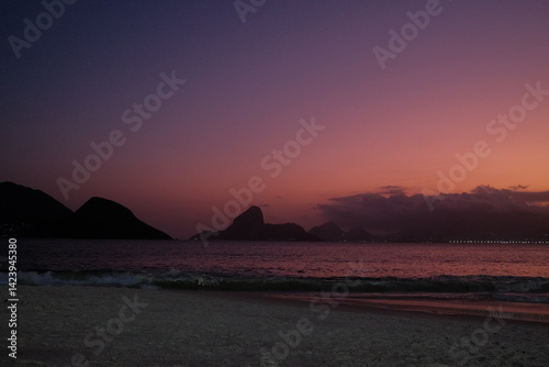 Fotografie Pôr do sol vibrante na Praia de Icaraí, em Niterói, com vista para o Pão de Açúcar, Baía de Guanabara e o skyline do Rio de Janeiro sob tons de rosa, roxo e laranja