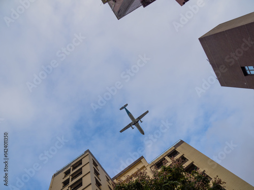 An airplane flying low over the buildings in the Datong District while it's landing on the Songshan Airport.