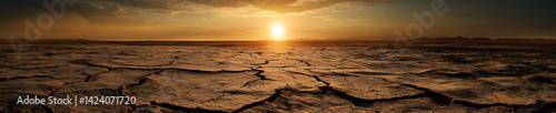 Wide panorama of desolate cracked terrain with the sun faintly visible through the dust storm, drought and desertification concept.