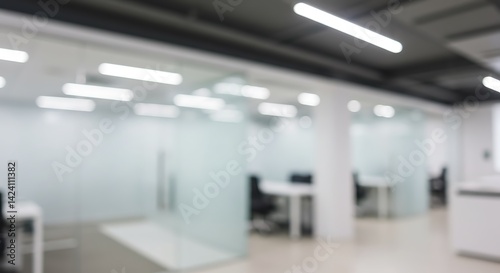 Fototapeta Naklejka Na Ścianę i Meble -  Blurred view of a modern office space with glass walls and bright lighting fixtures overhead shown here