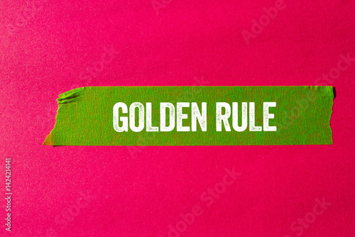 Golden rule message written on ripped torn green paper tape on pink background. Conceptual golden rule symbol. Copy space.