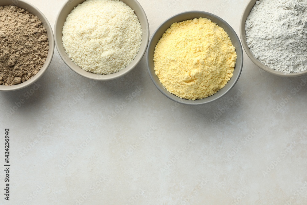 Different types of flour in bowls on light grey table, flat lay. Space for text